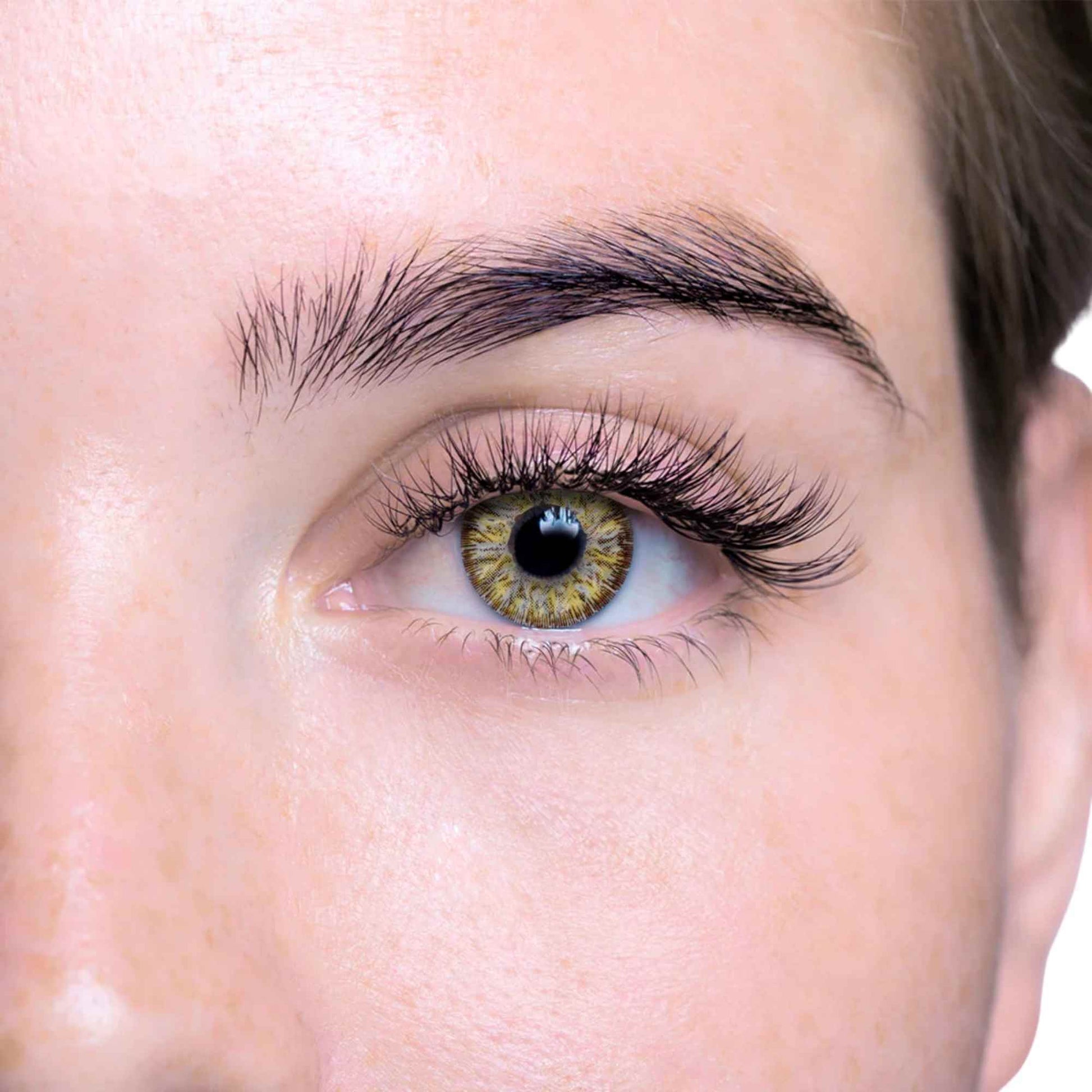 Close-up of a person's eye with gold and grey contact lens on a white background
